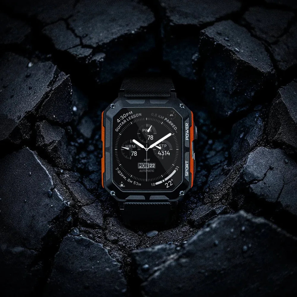 Black and orange rugged smart watch on a dark stone surface
